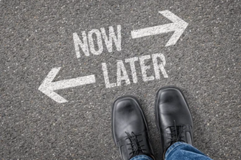 Op beton gespoten pijlen met naar rechts 'now' en naar links 'later'. Met daarvoor een bovenaanzicht van herenschoenen (iemand die voor deze keuze staat).